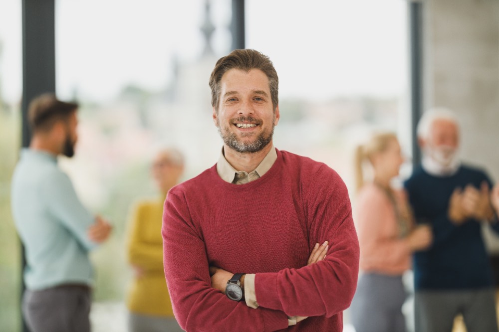 Smiling man in a red sweater with arms crossed